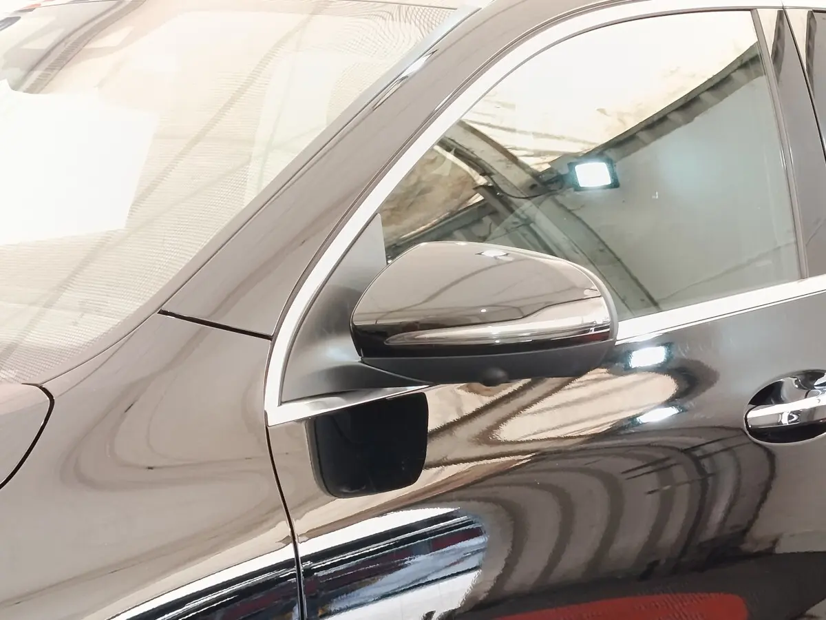 Vue rapprochée du côté gauche d’un Mercedes GLA 250 e AMG Line noir, mettant en valeur le rétroviseur et la poignée de porte.
