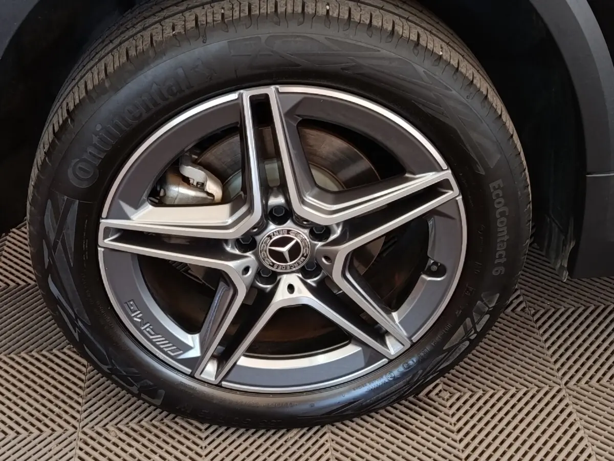Gros plan sur la roue avant droite avec jante AMG gris métallisé du Mercedes GLA 250 e noir hybride rechargeable.