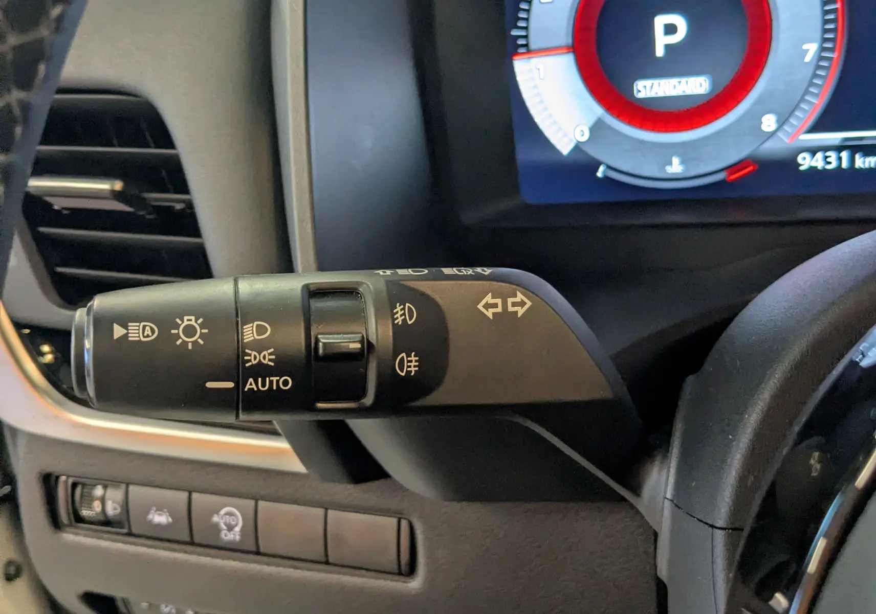 Gros plan sur la commande des feux et clignotants du Nissan Qashqai blanc 2024, tableau de bord numérique visible.