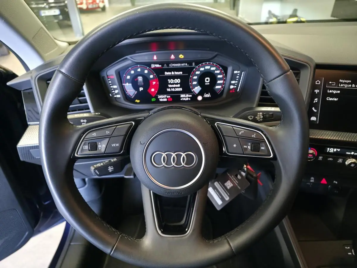 Volant cuir multifonctions Audi A1 Sportback 2024 vu de face avec tableau de bord digital et écran central noir.
