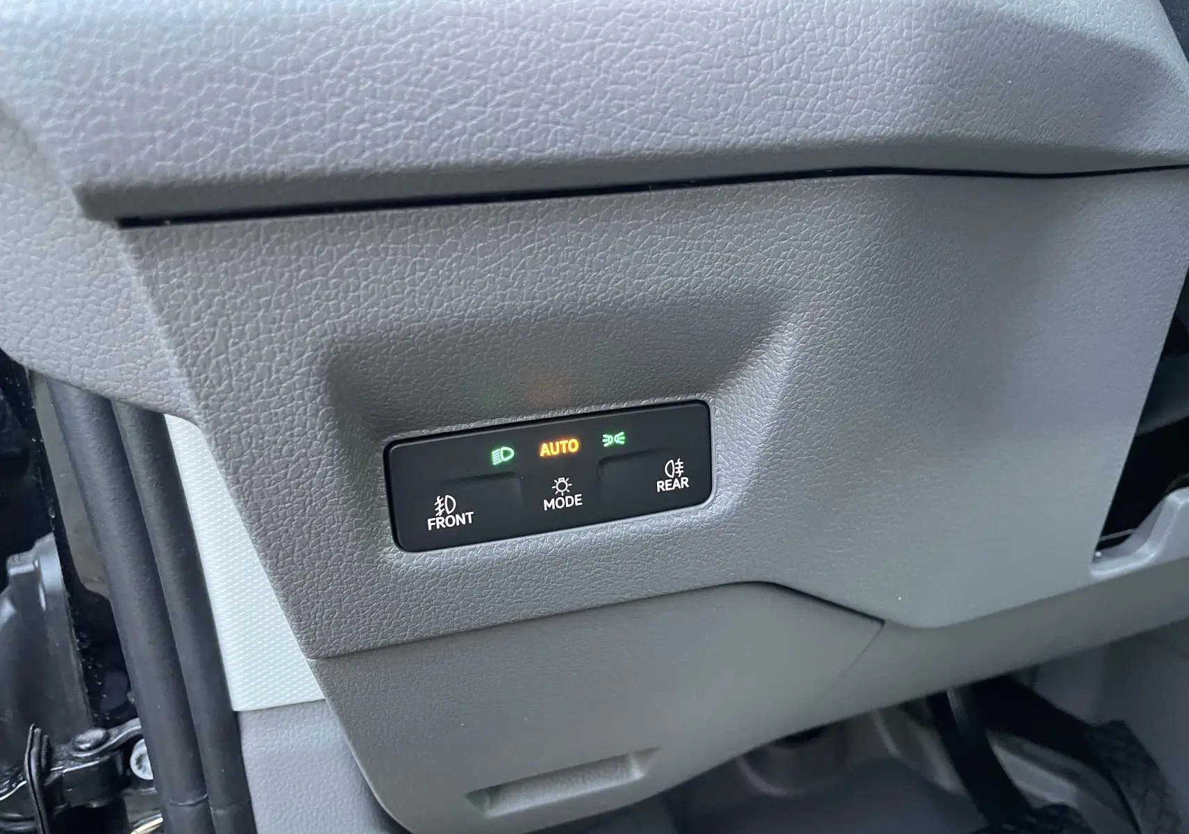 Bouton de commande des phares avec éclairage automatique dans l'habitacle gris du Volkswagen Crafter Van noir intense 2025.
