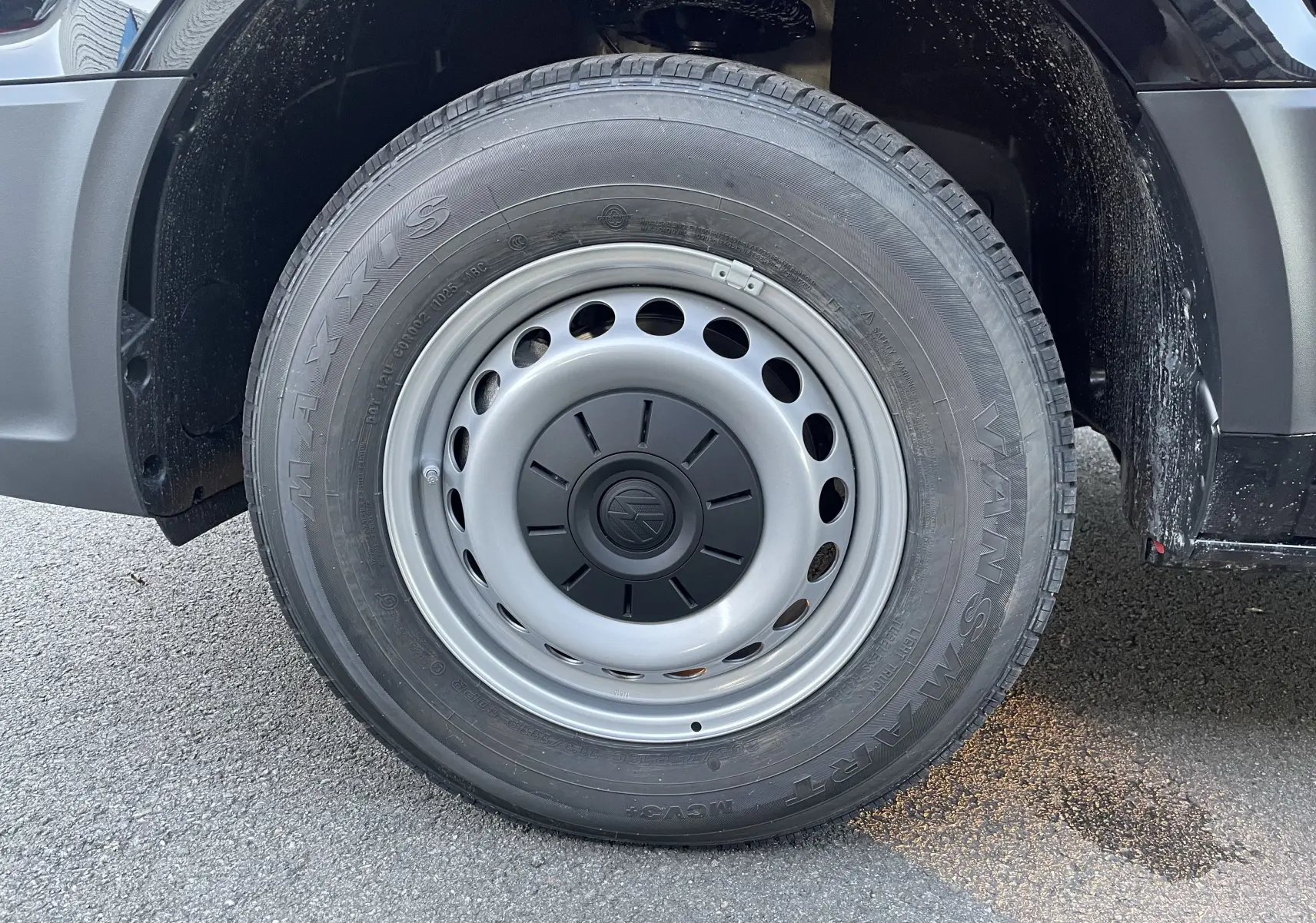 Gros plan sur la roue avant droite du Volkswagen Crafter Van noir intense, jante acier avec logo VW central.