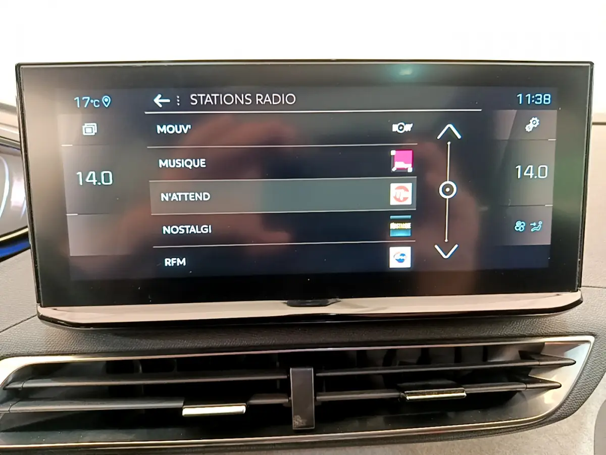 Écran tactile central affichant les stations radio dans l'habitacle d'une Peugeot 3008 GT rouge, vue de face.