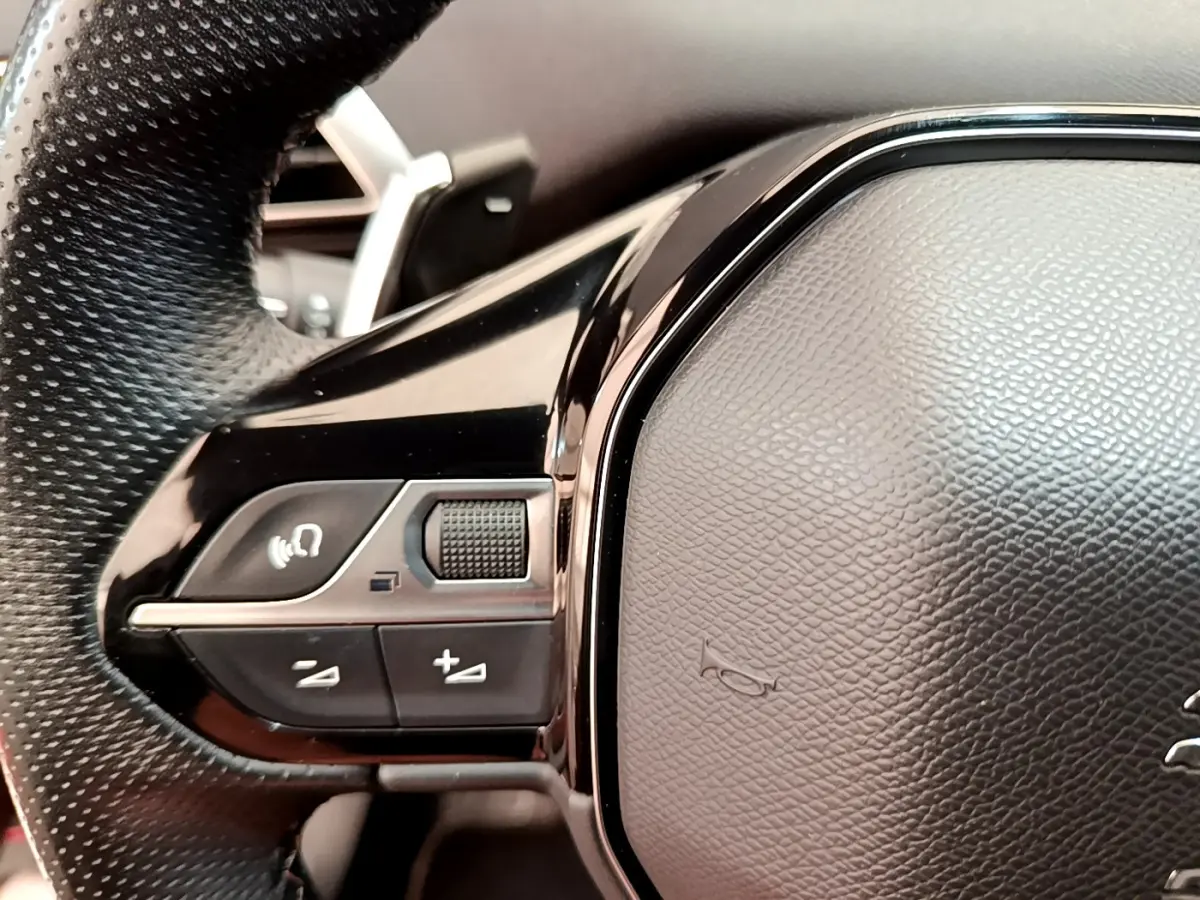 Gros plan sur les commandes gauche du volant cuir noir du Peugeot 3008 Rouge 2021 BlueHDi GT.