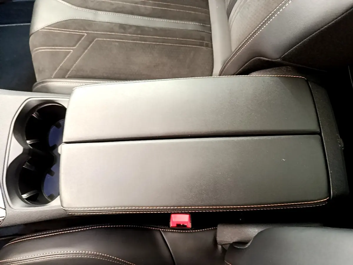 Vue rapprochée du couvercle de la console centrale noire avec surpiqûres orange du Peugeot 3008 GT 2021.