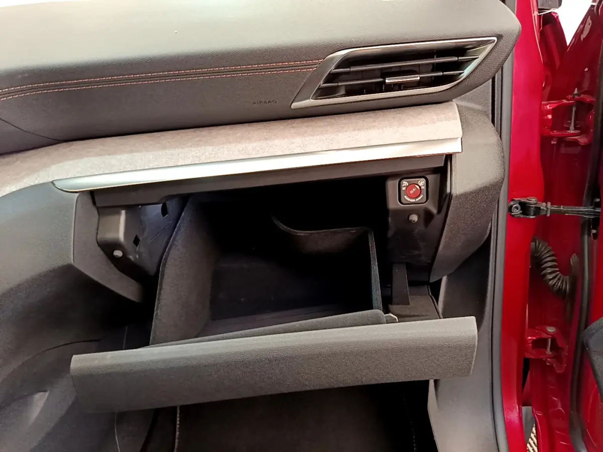 Vue intérieure côté passager du Peugeot 3008 rouge 2021, boîte à gants ouverte sous tableau de bord gris avec surpiqûres rouges.