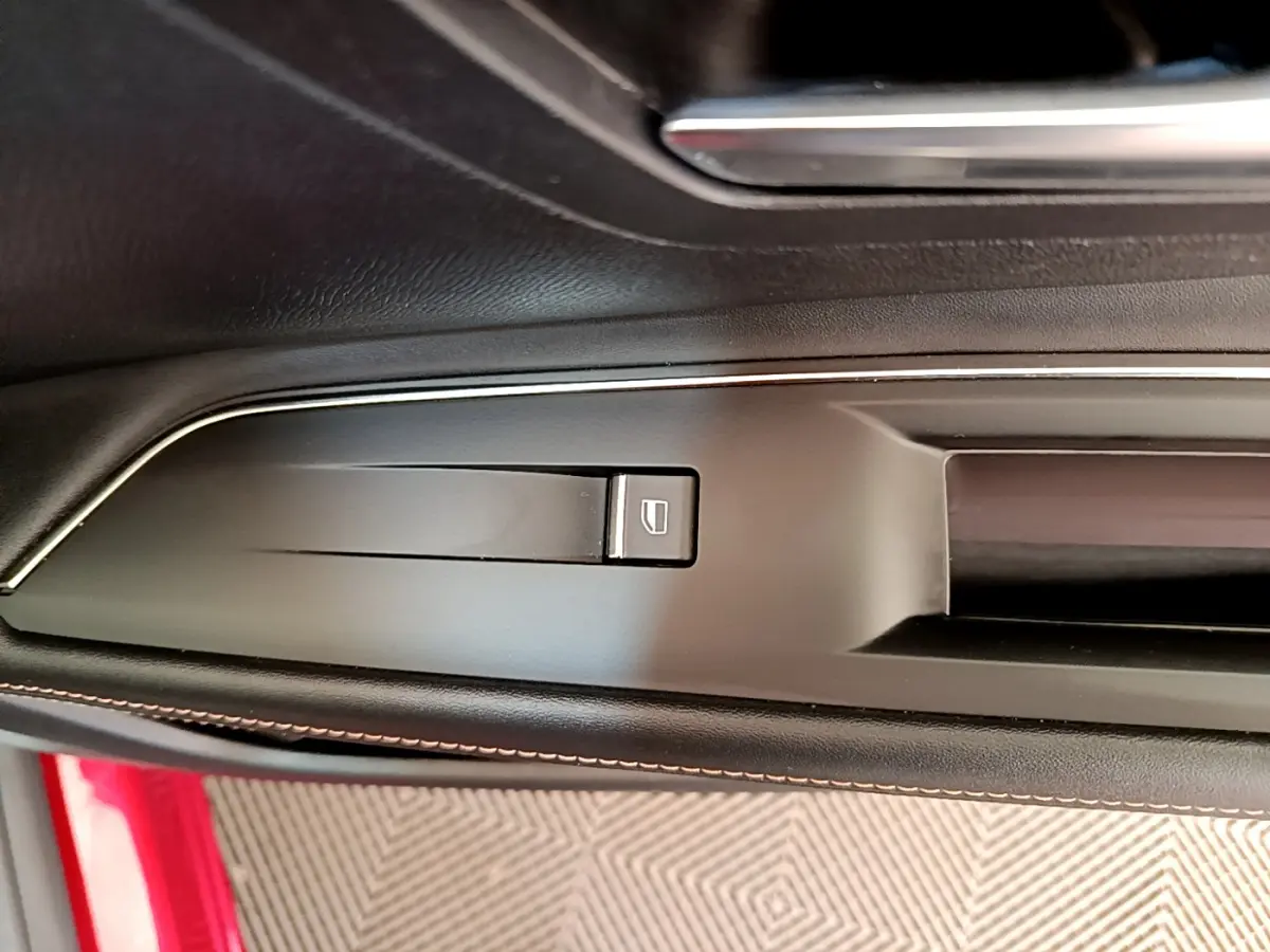Détail de la commande de verrouillage des portes sur la portière côté gauche d’un Peugeot 3008 rouge.