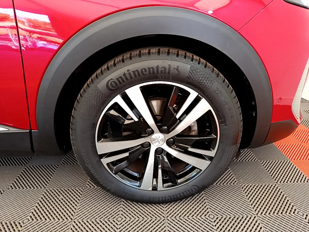 Gros plan sur la roue avant gauche d’un Peugeot 3008 rouge, avec jante alliage bicolore et pneu Continental.