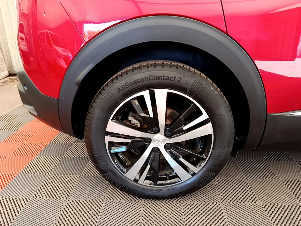 Gros plan sur la roue arrière droite du Peugeot 3008 rouge, avec jante alliage bicolore et pneus Continental.