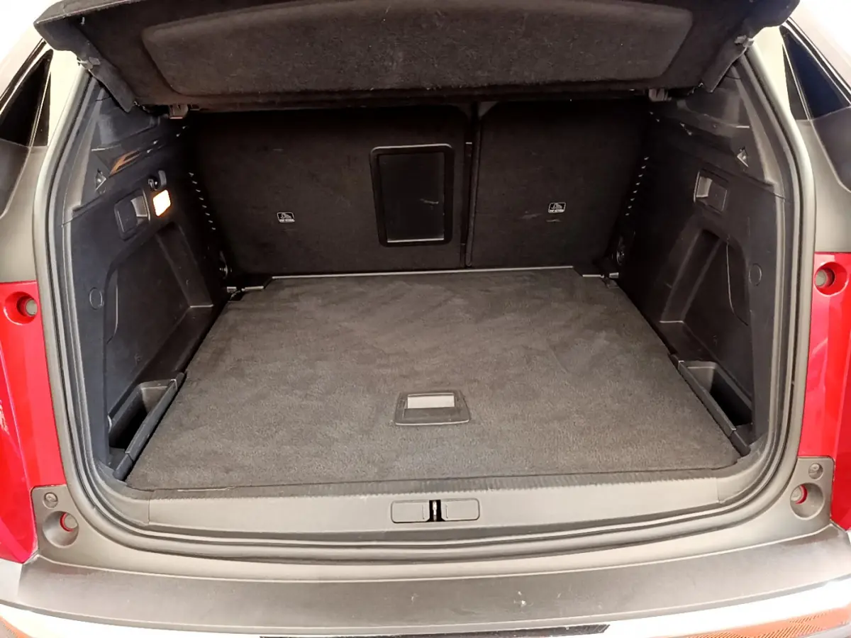 Coffre ouvert vu de l'arrière d'un Peugeot 3008 rouge, montrant un espace de chargement propre et bien fini.