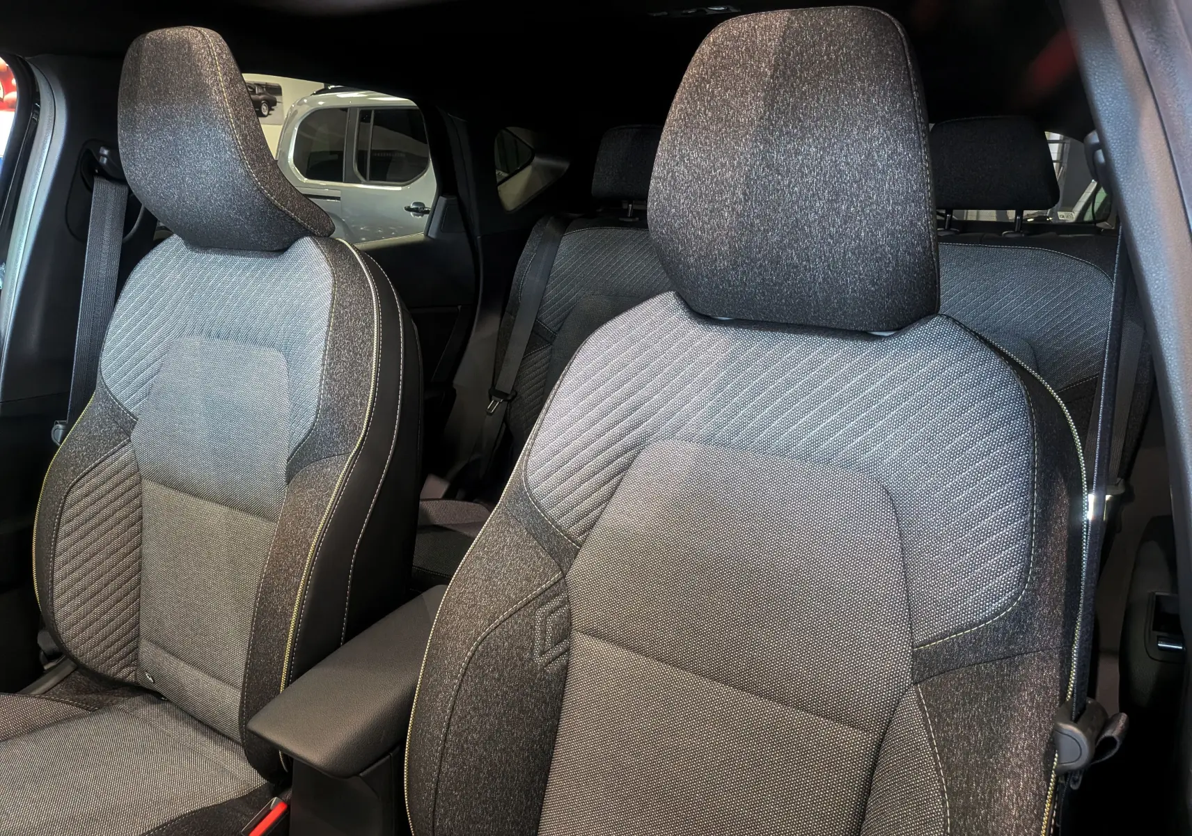 Vue intérieure sur les sièges avant tissu gris et noir du Renault Captur E-TECH 2026, avec accoudoir central visible.
