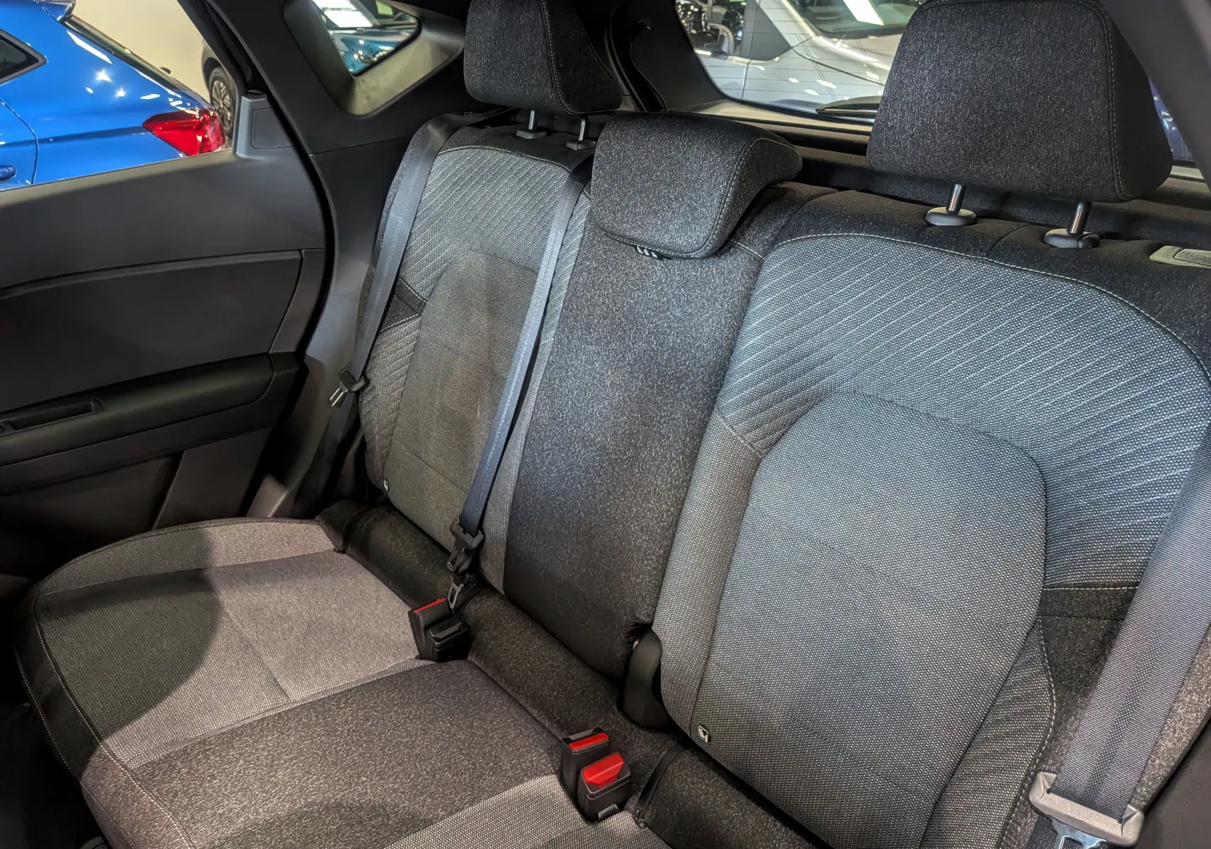 Vue intérieure sur les sièges arrière en tissu gris du Renault Captur E-TECH Full Hybrid 2026, avec ceinture de sécurité visible.