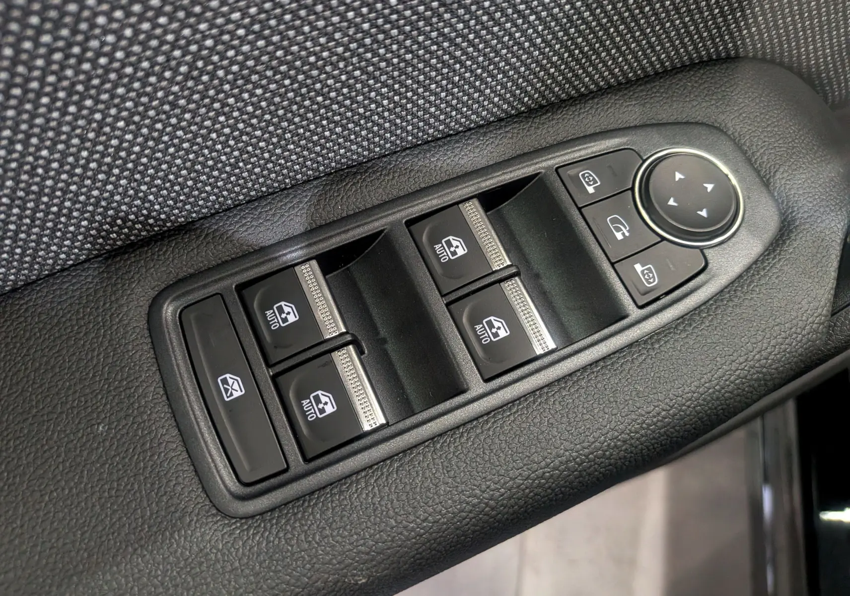 Panneau de commandes des vitres électriques et rétroviseurs sur la porte côté gauche d’un Renault Captur noir, intérieur tissu gris.