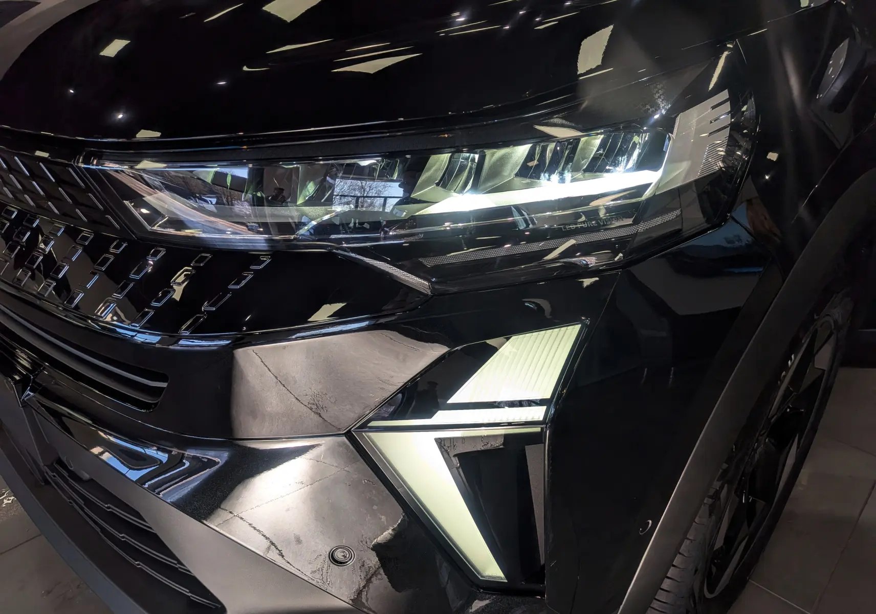 Gros plan sur l'avant droit noir brillant du Renault Captur E-Tech 2026, mettant en valeur ses phares LED et sa calandre distinctive.