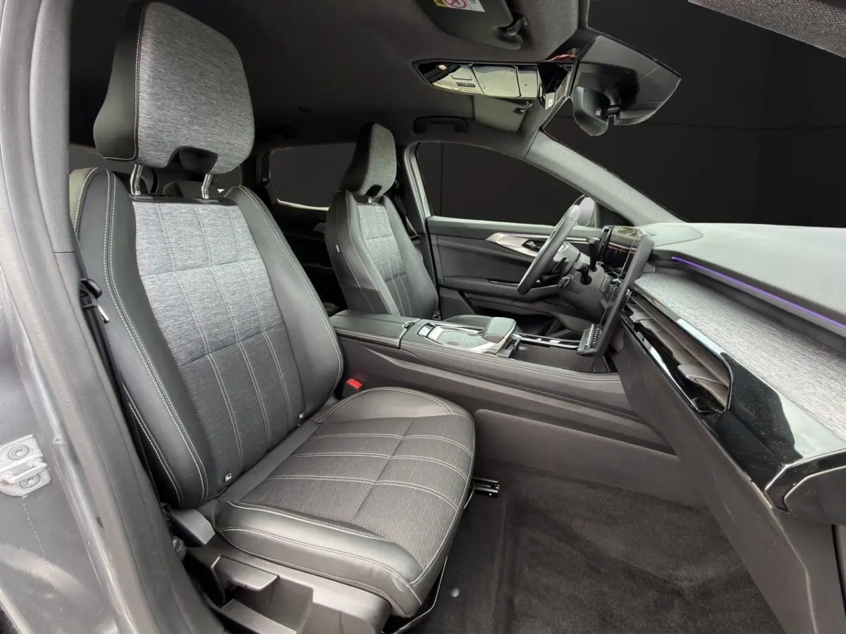 Vue intérieure côté conducteur du Renault Austral 2025, sièges tissu gris et cuir noir avec tableau de bord moderne et écran tactile.