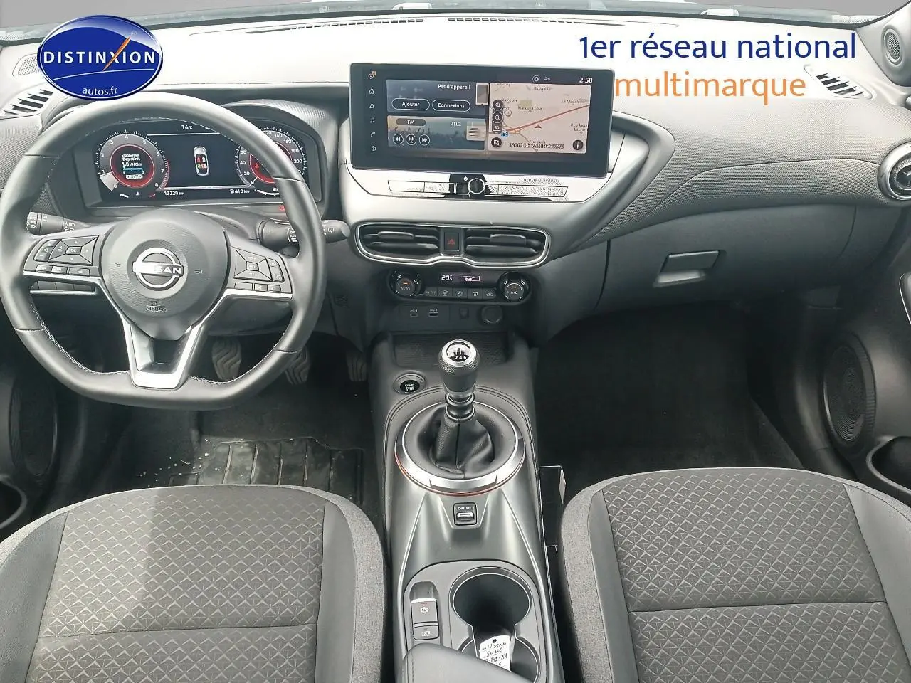 Intérieur de Nissan Juke 2025 vue avant, tableau de bord noir avec écran tactile et levier de vitesses manuel.