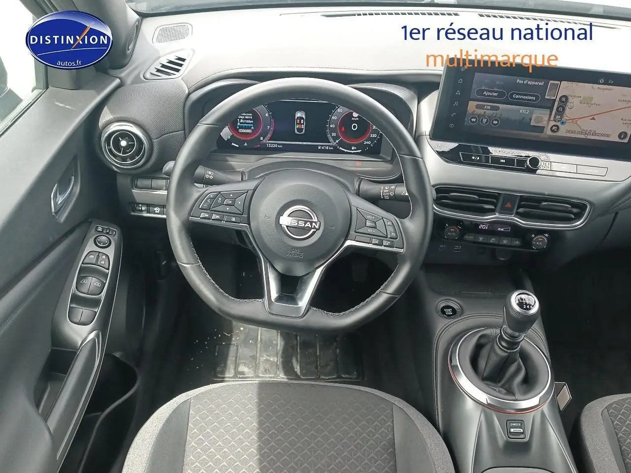Vue intérieure centrée sur le volant cuir multifonction et levier de vitesse manuel du Nissan Juke gris 2025.