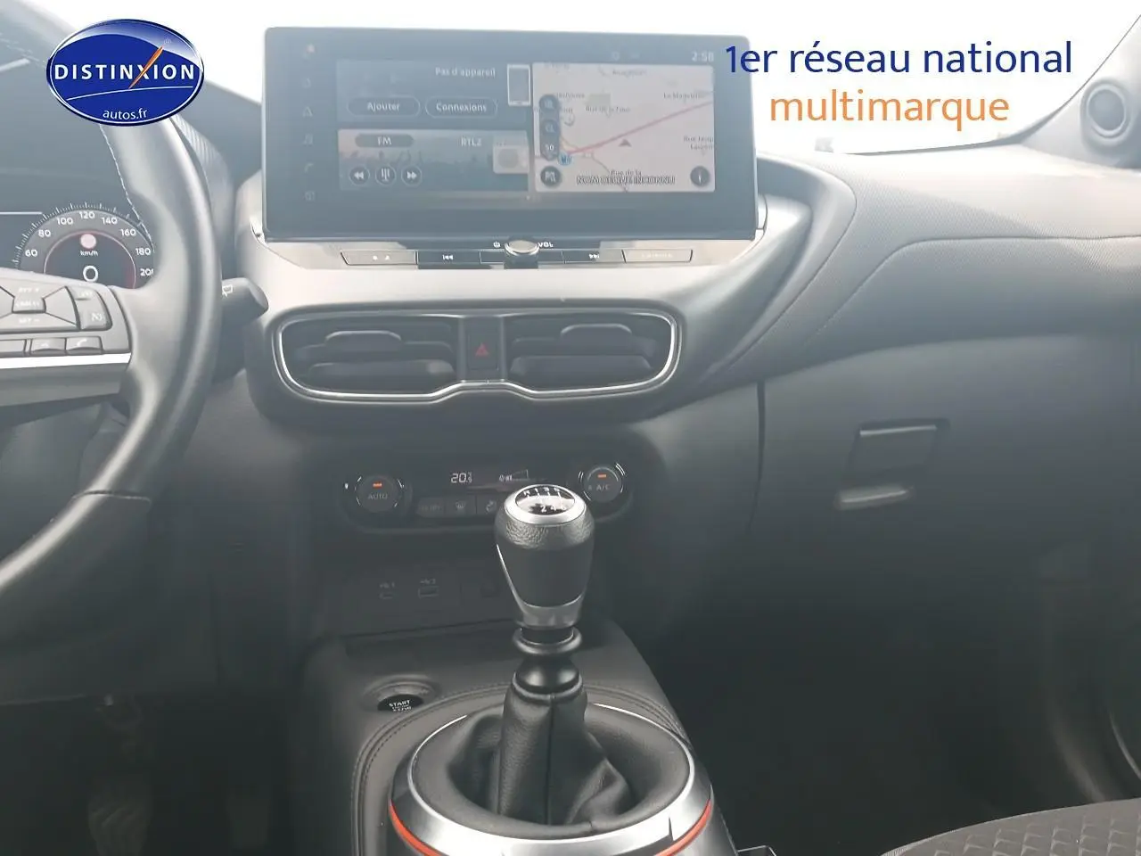 Intérieur de Nissan Juke gris 2025, vue centrée sur levier de vitesse manuel et écran tactile multifonction.