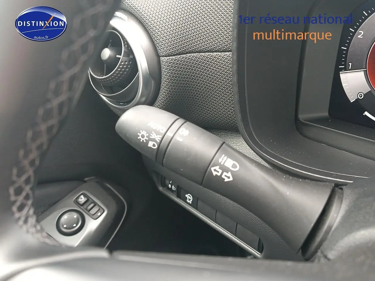 Gros plan sur la commande des clignotants et phares du tableau de bord noir du Nissan Juke gris 2025.