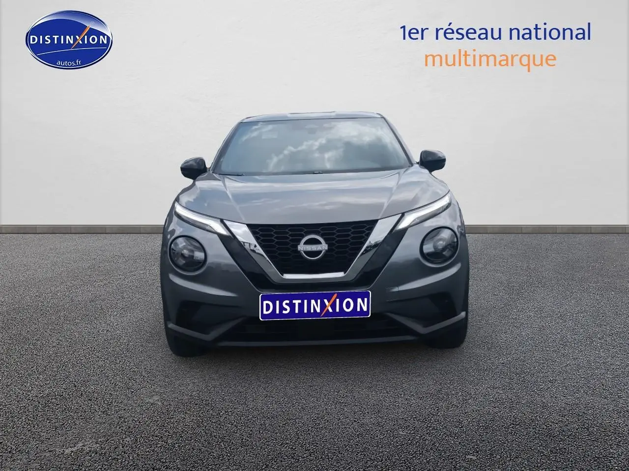 Vue frontale d'un Nissan Juke gris 2025 avec calandre en V caractéristique et phares ronds distinctifs.