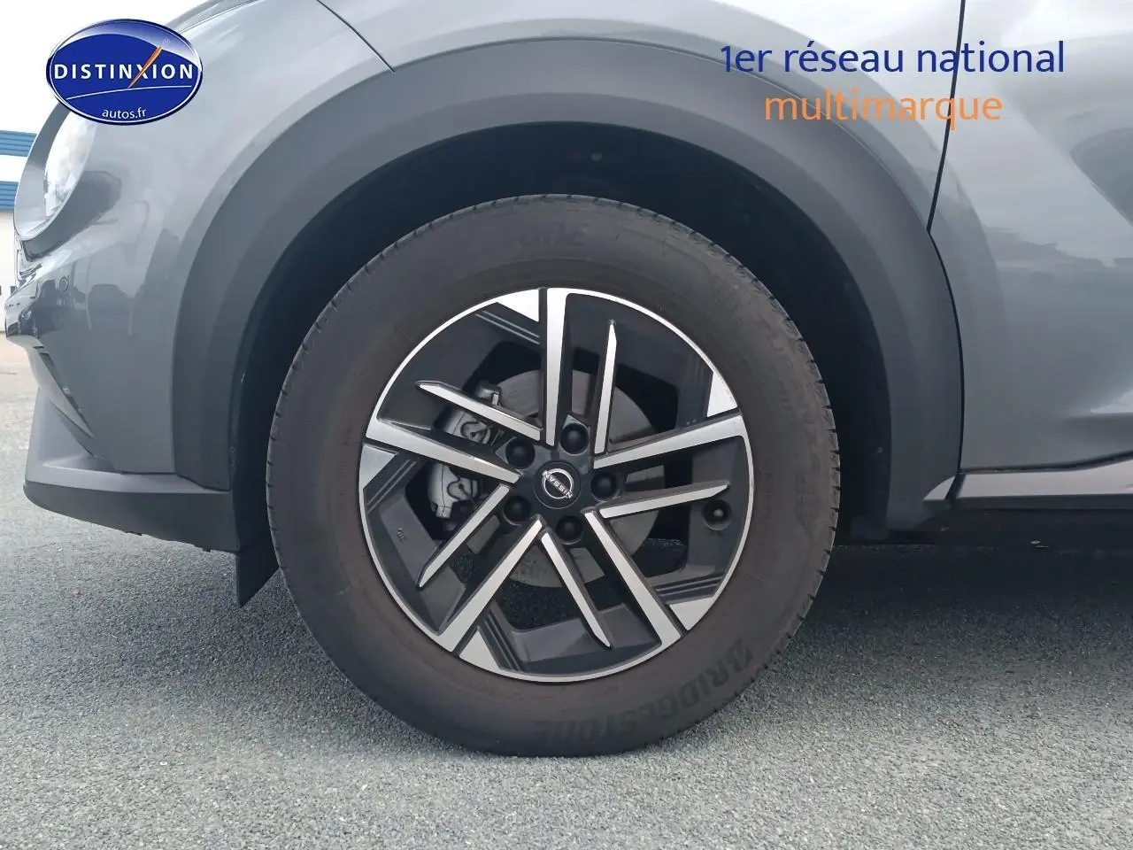 Gros plan sur la roue avant gauche du Nissan Juke gris 2025 avec jante alliage noire et argent.