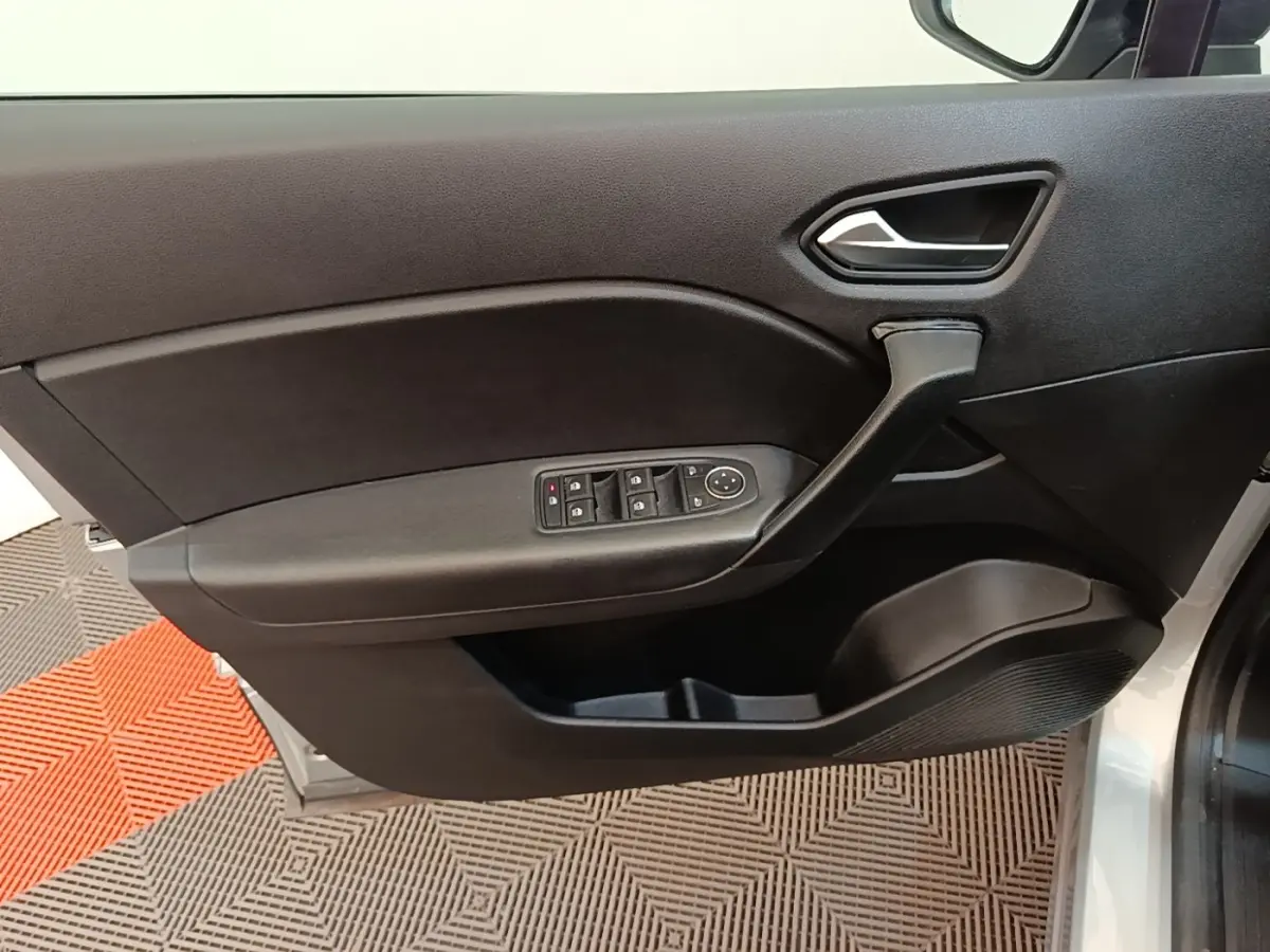 Vue rapprochée de la porte avant gauche noire du Renault Captur gris clair, avec commandes électriques des vitres.