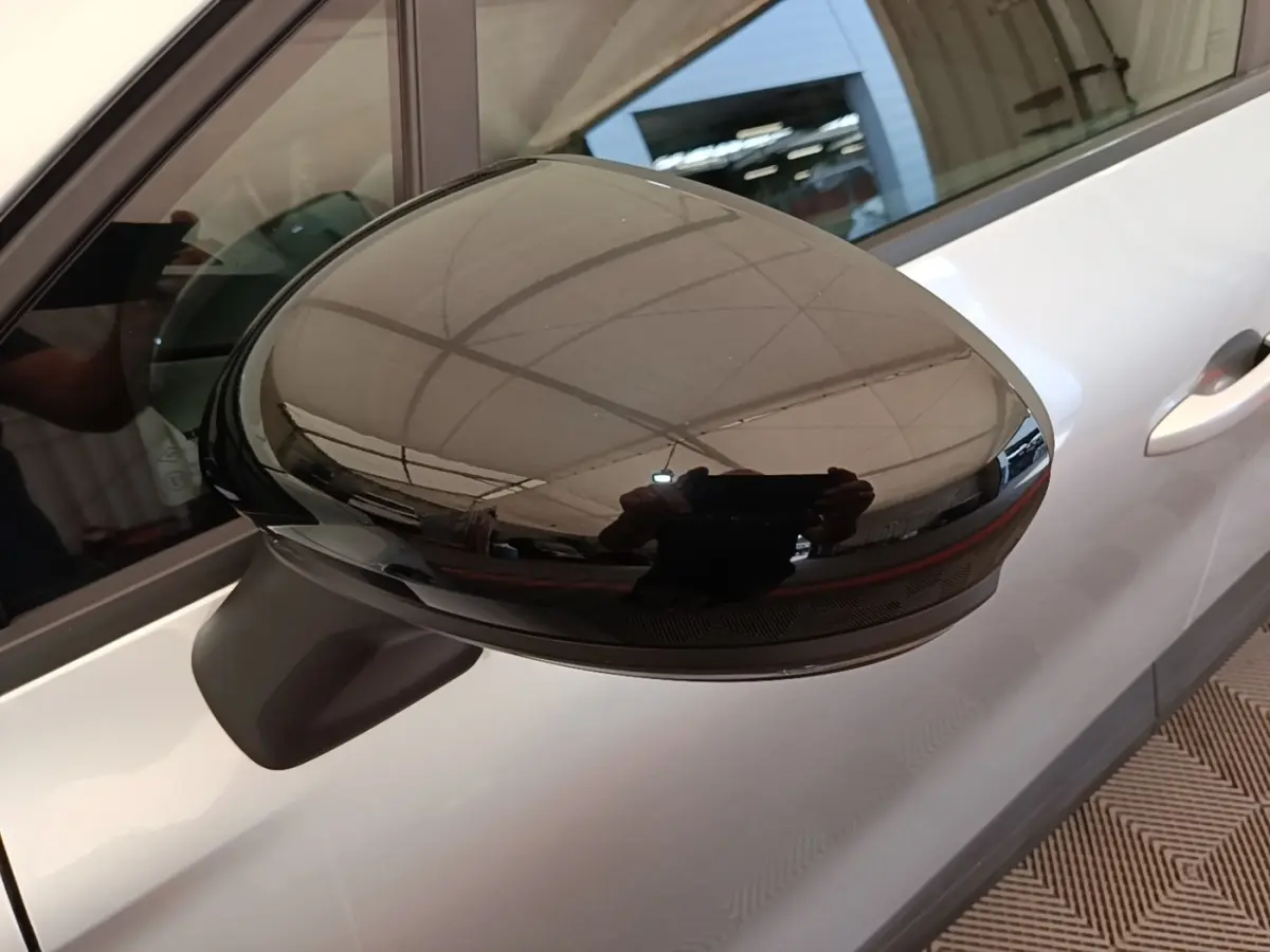 Gros plan sur le rétroviseur noir brillant côté gauche du Renault Captur Business E-Tech gris clair, vue latérale partielle.