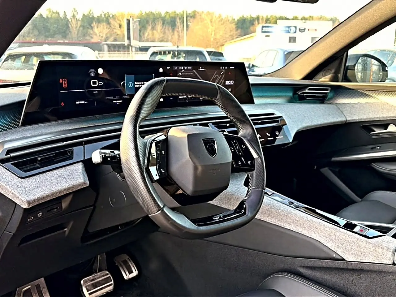 Vue intérieure avant du Peugeot 3008 gris 2025, volant cuir multifonction et tableau de bord numérique large.