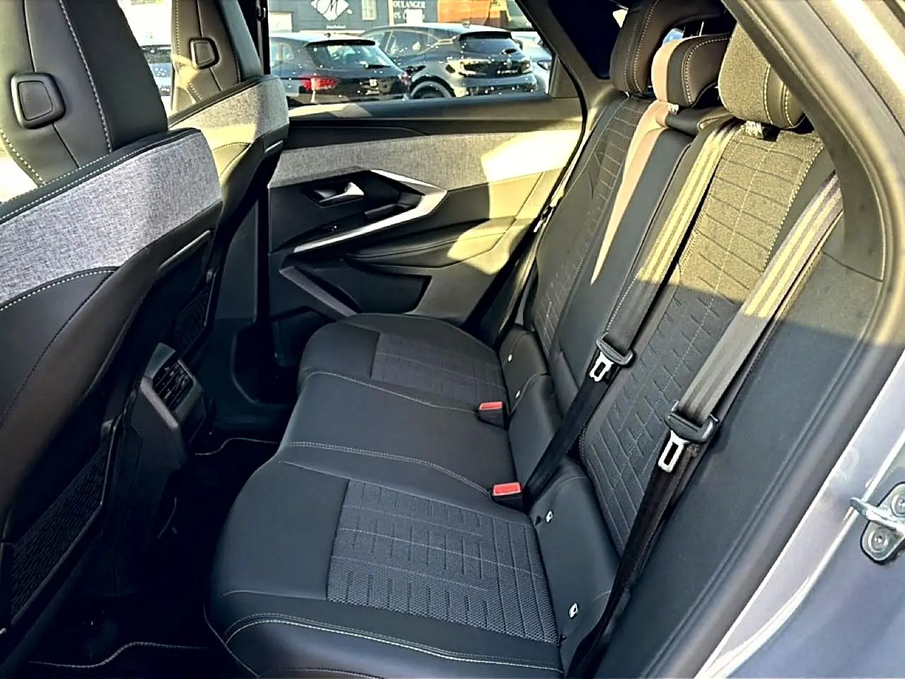 Vue latérale droite de l'intérieur arrière du Peugeot 3008 gris, montrant les sièges en tissu et cuir avec ceintures de sécurité.