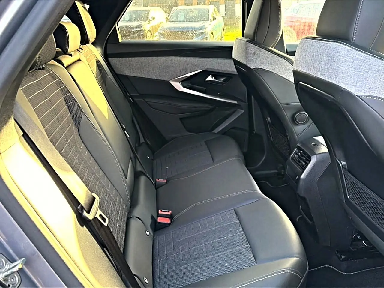 Vue intérieure arrière côté gauche du Peugeot 3008 gris 2025, sièges en tissu et cuir avec surpiqûres claires.