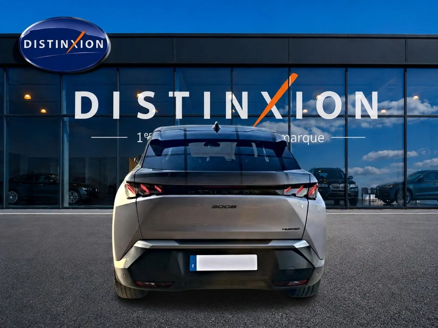 Vue arrière d’un Peugeot 3008 gris 2025 avec feux arrière LED distinctifs, stationné devant une vitrine Distinxion.