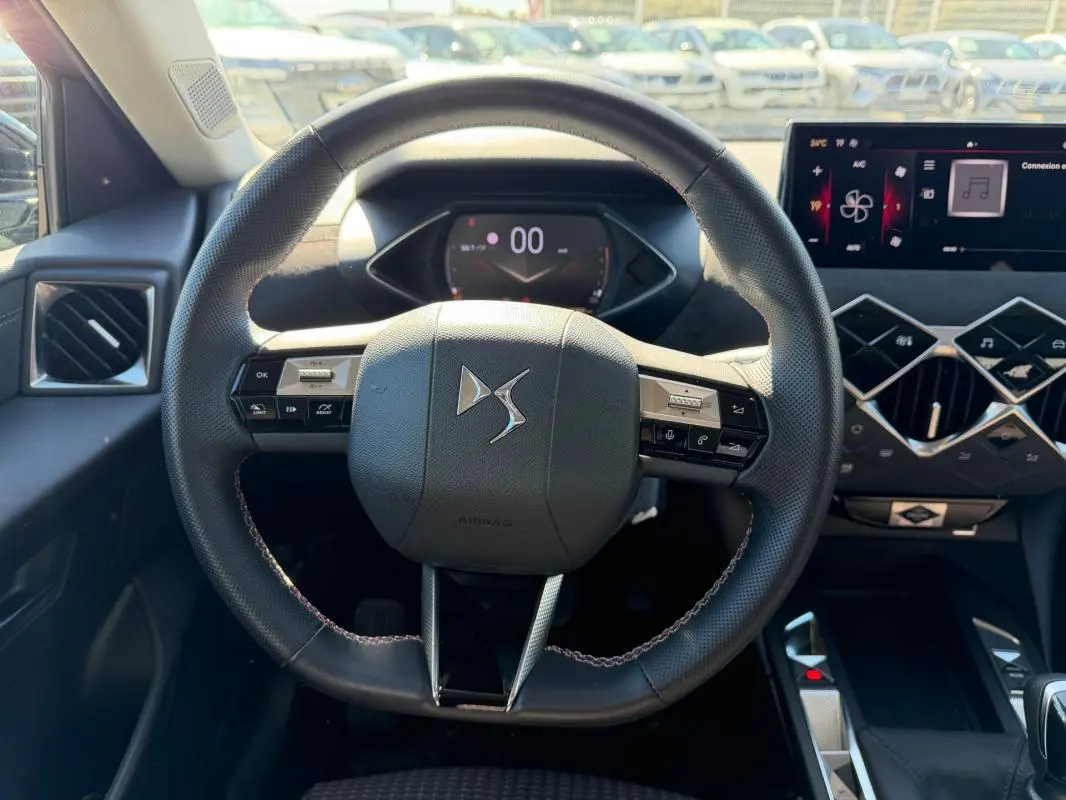 Vue intérieure centrée sur le volant du DS3 100 BVM6 Performance Line 2024, avec tableau de bord et écran tactile visibles.