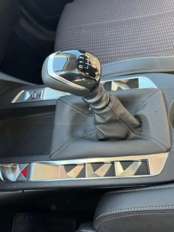 Le levier de vitesses manuel noir du DS3 100 BVM6 Performance Line 2024, avec console grise et sièges tissu à motifs.