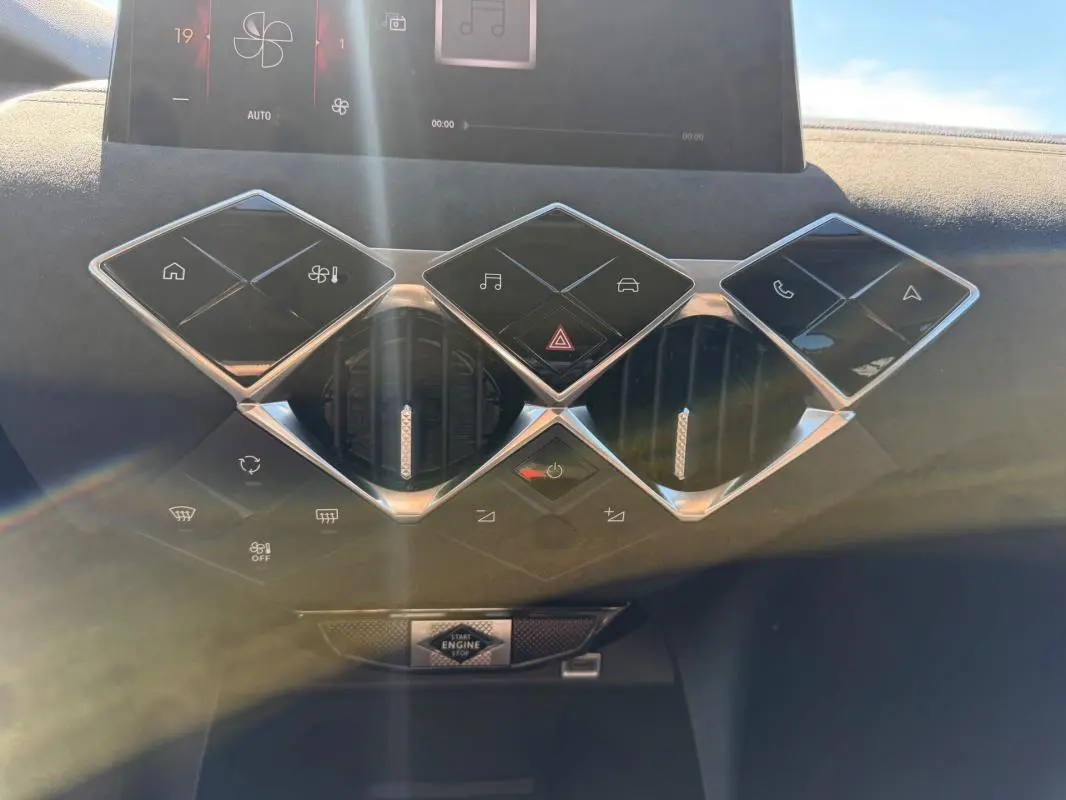 Vue rapprochée de la console centrale du DS3 2024 gris, avec commandes tactiles en losange et aérateurs ronds chromés.
