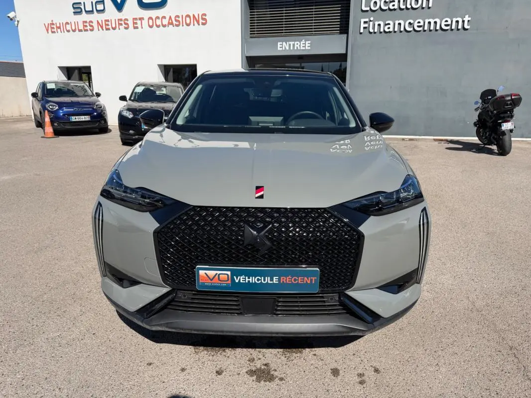 Vue de face d'une DS3 100 BVM6 Performance Line gris 2024 avec calandre noire et phares effilés, sur parking extérieur.