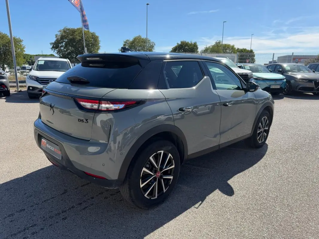 Vue 3/4 arrière droite d'une DS3 100 BVM6 Performance Line gris métallisé avec toit noir et jantes alliage bicolores.