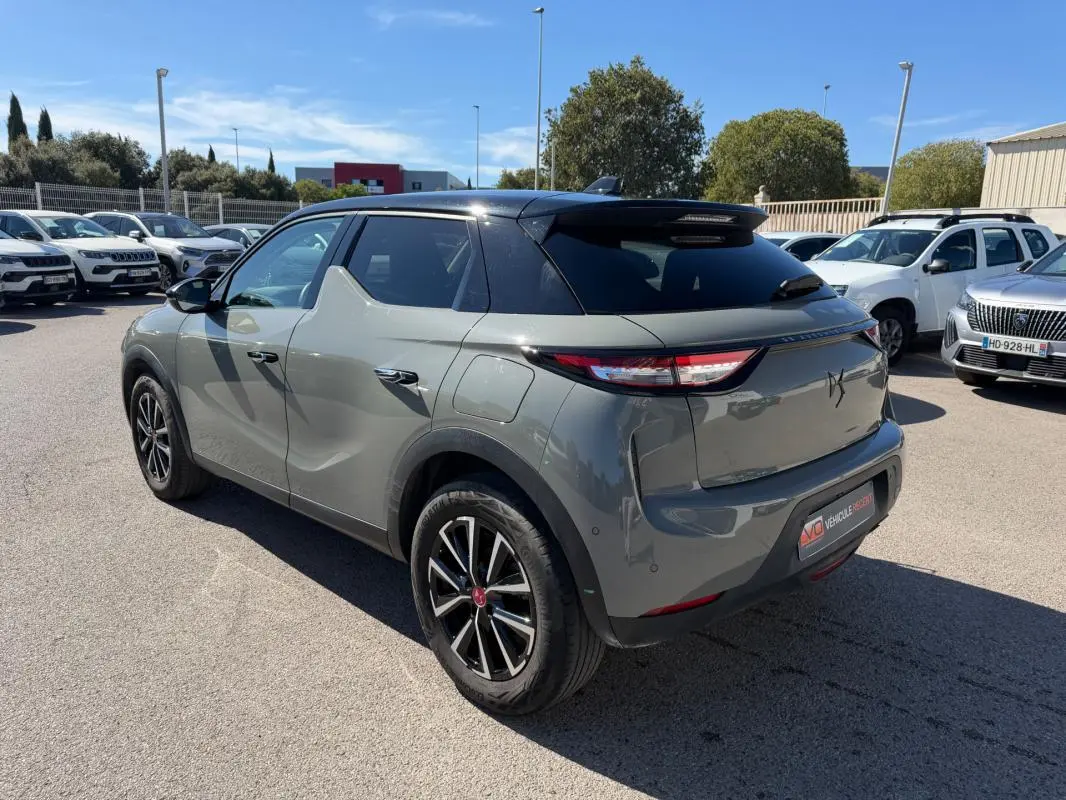 Vue 3/4 arrière droite d'une DS3 100 BVM6 Performance Line gris avec toit noir, garée en extérieur par temps ensoleillé.