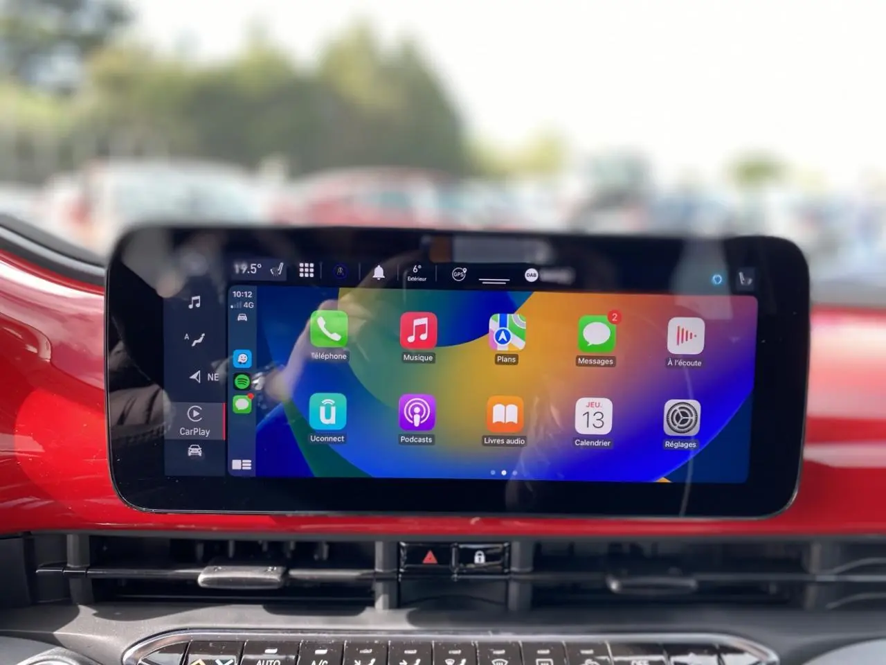 Écran tactile central affichant Apple CarPlay dans l’habitacle rouge vif d’une Fiat 500 Cabriolet électrique.