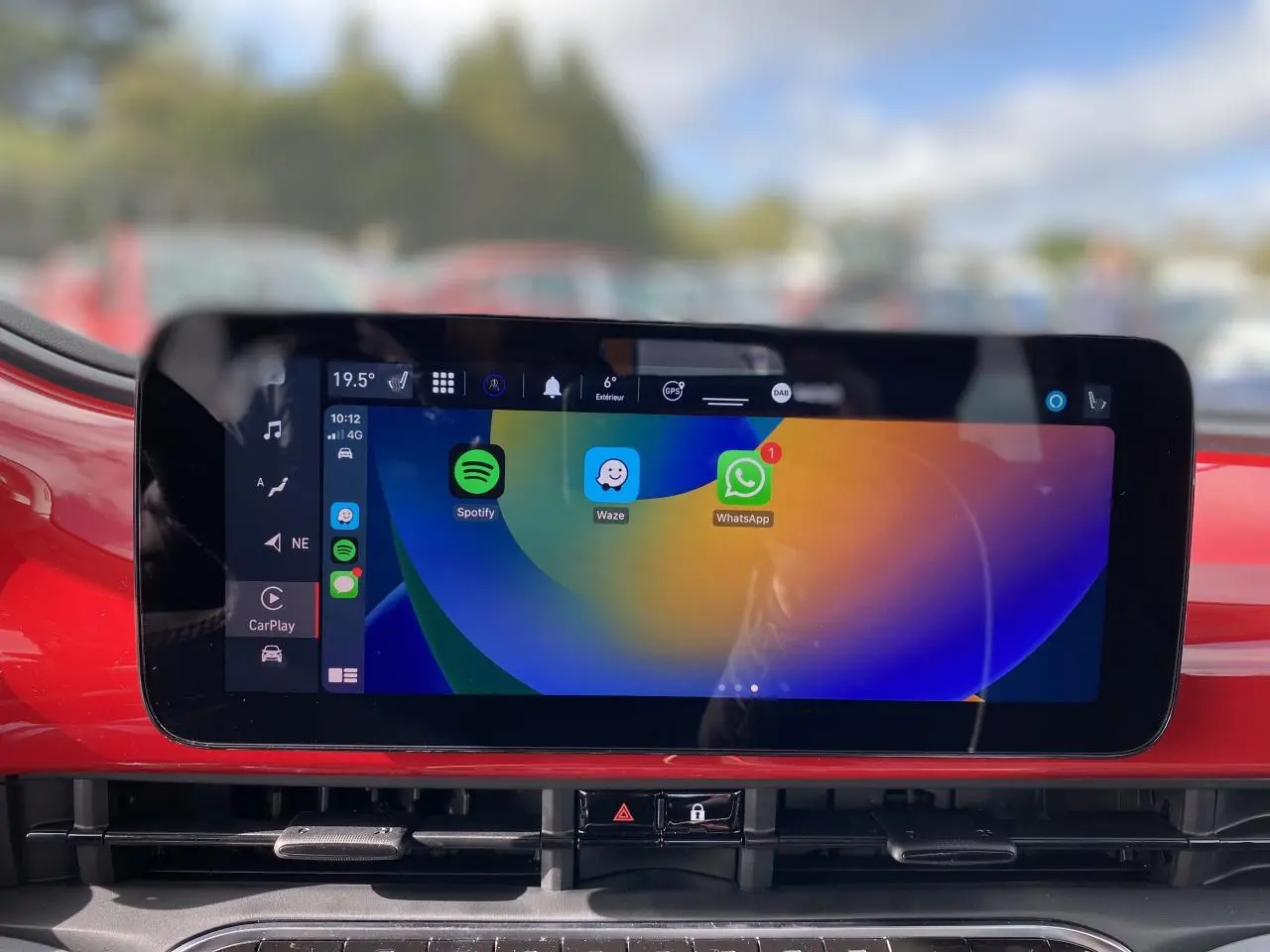 Écran tactile central affichant Spotify, Waze et WhatsApp sur tableau de bord rouge d'une Fiat 500 Cabriolet Electrique 2022.