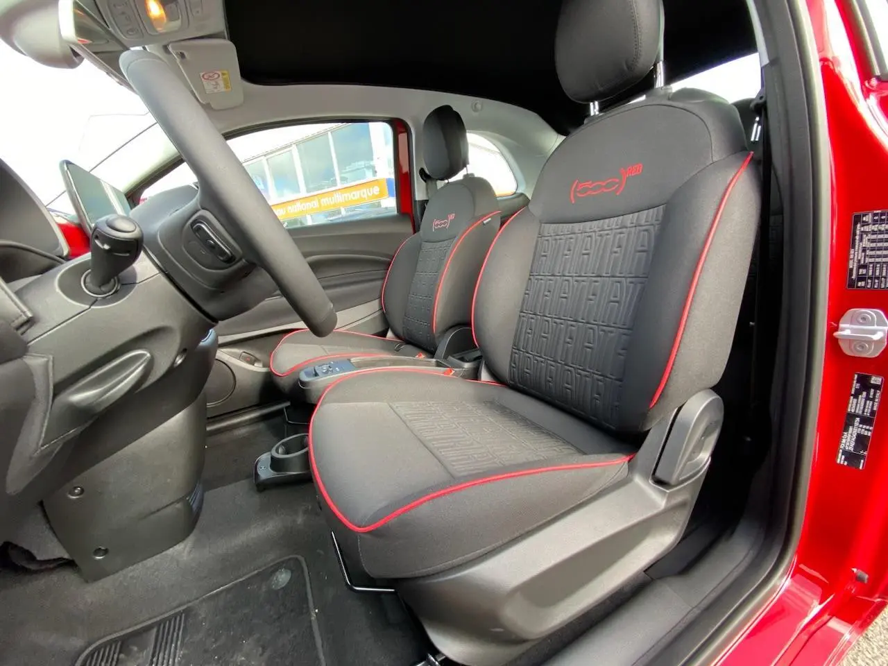 Intérieur côté conducteur du Fiat 500 Cabriolet Electrique rouge, sièges noirs avec surpiqûres rouges et logo 500 RED brodé.