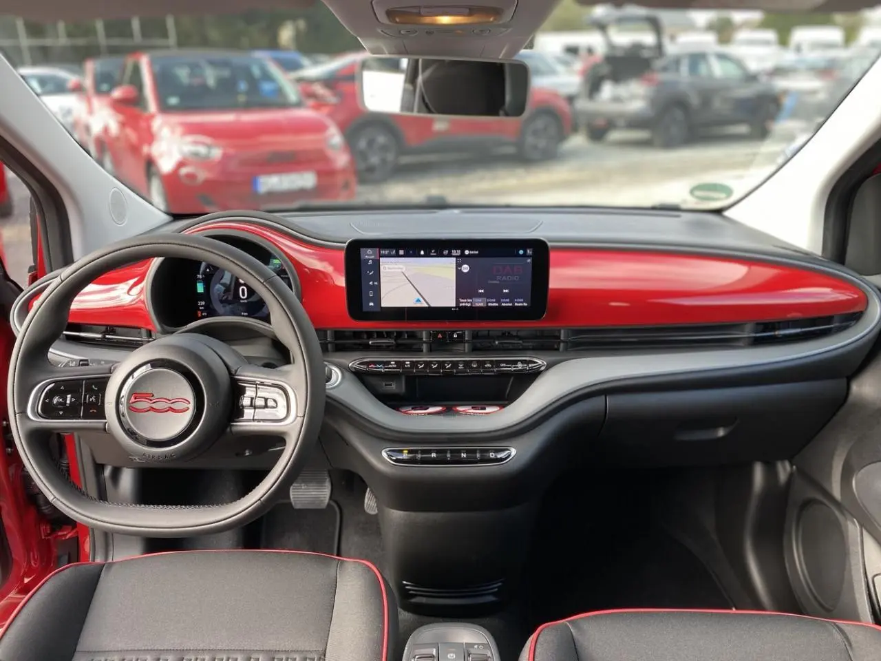 Intérieur de la Fiat 500 Cabriolet Electrique rouge, vue frontale sur le tableau de bord et volant avec écran tactile.