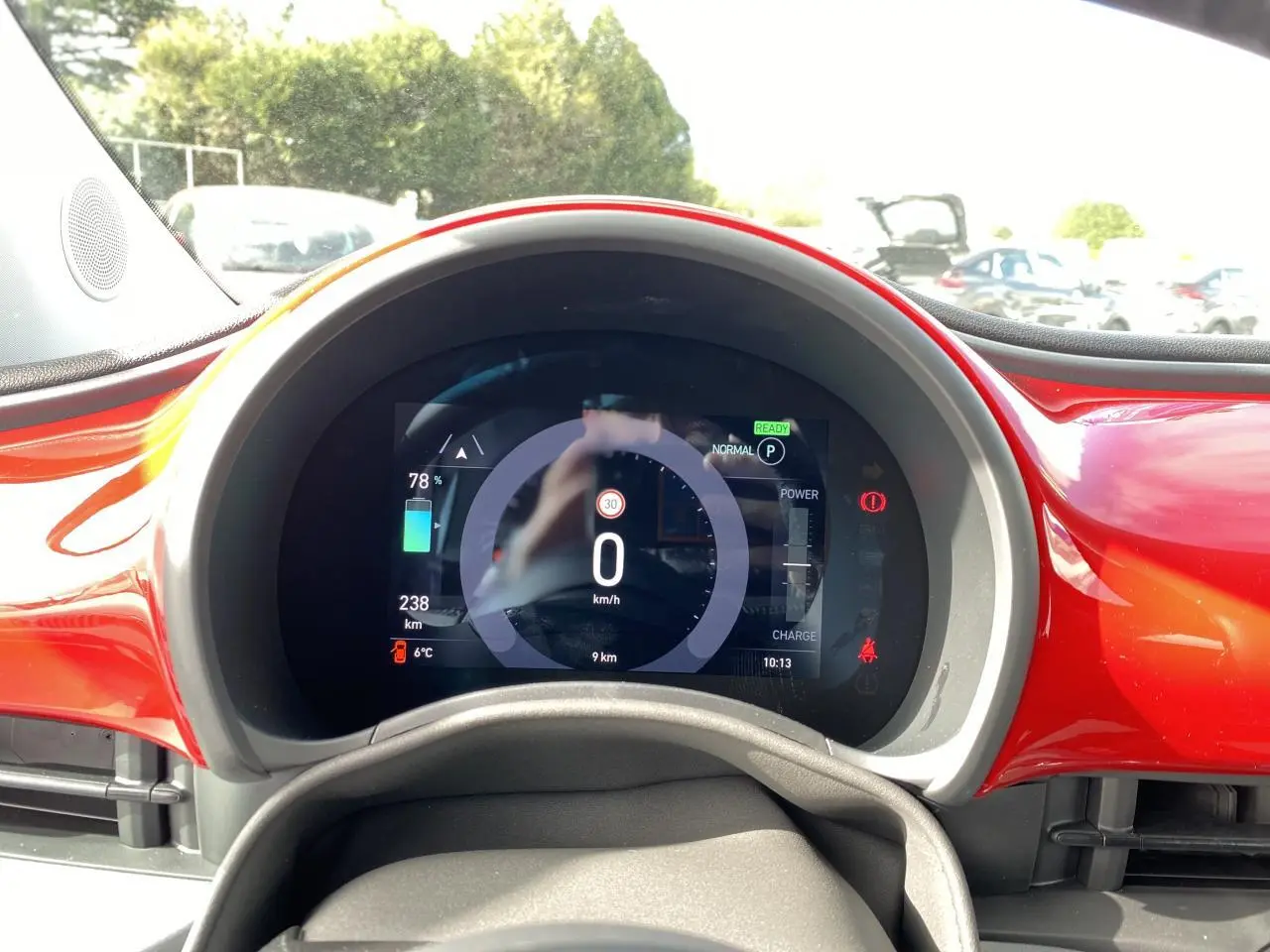 Tableau de bord numérique de la Fiat 500 Cabriolet Electrique rouge, affichant vitesse et autonomie, vue frontale rapprochée.