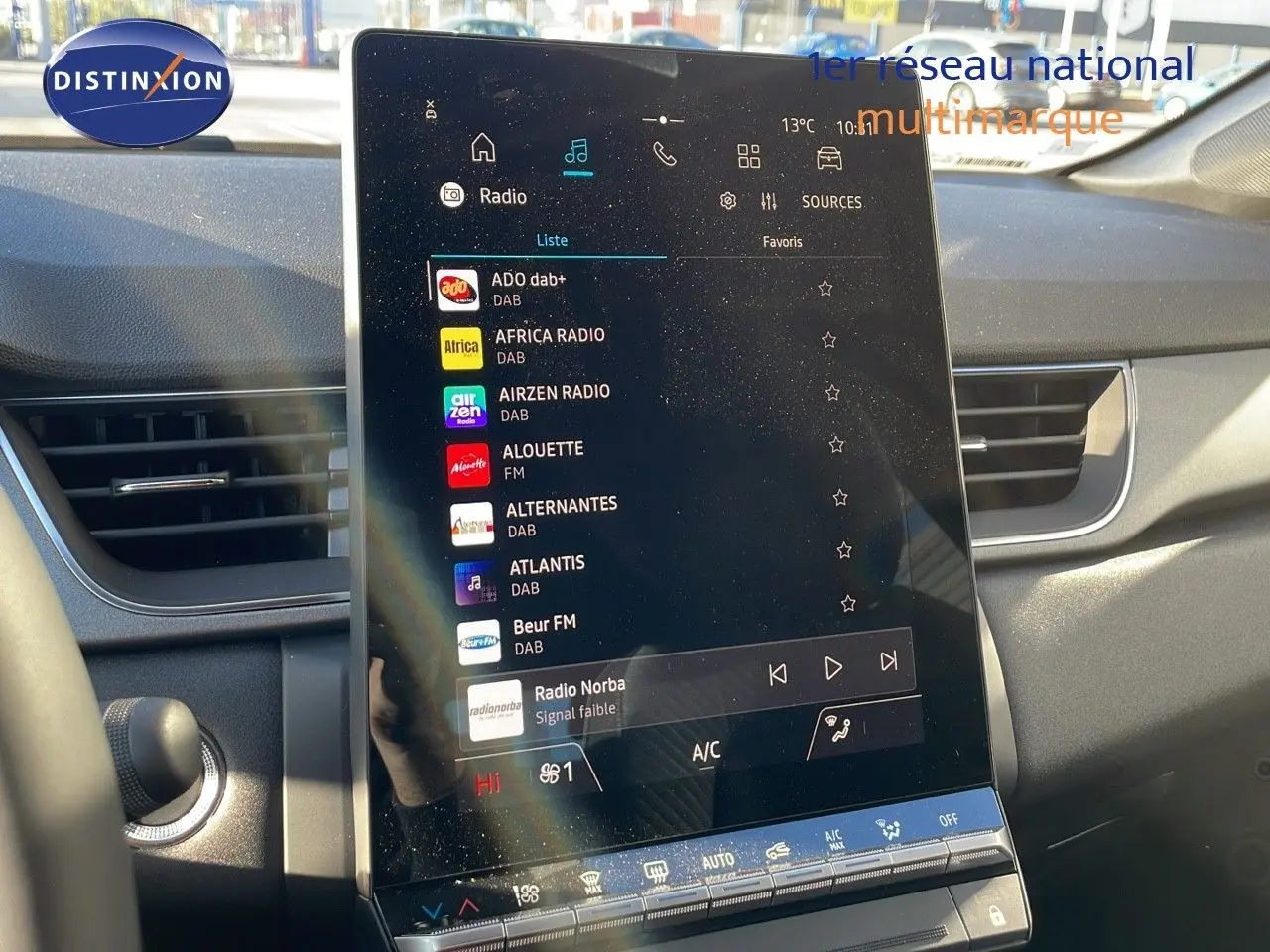 Écran tactile central allumé avec menu radio, intérieur gris du Renault Captur E-Tech hybride 2025 visible de face.