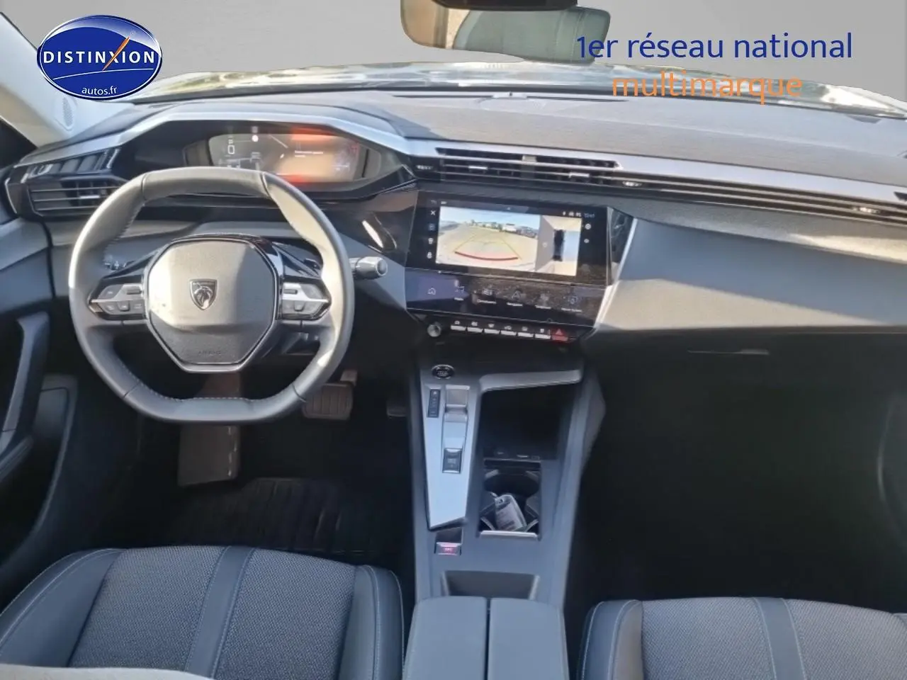 Vue intérieure avant du Peugeot 408 Hybrid 145 allure e-dcs6 noir, avec volant cuir et écran tactile affichant la caméra de recul.