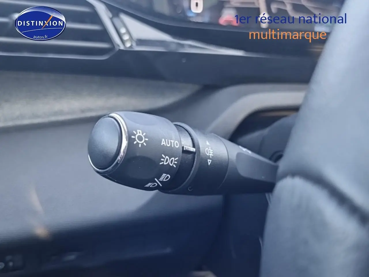 Gros plan sur la commande des phares à gauche du volant dans l’habitacle d’une Peugeot 408 noir 2025.