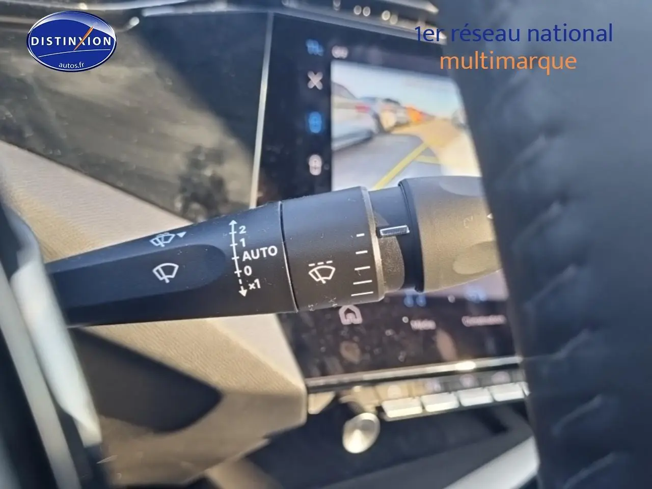 Gros plan sur la commande des essuie-glaces à gauche du volant cuir dans le Peugeot 408 noir, avec écran tactile en arrière-plan.