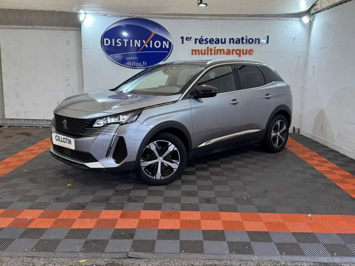 Peugeot 3008 BlueHDi gris clair vue 3/4 avant droit, avec jantes noires et toit noir dans un showroom.