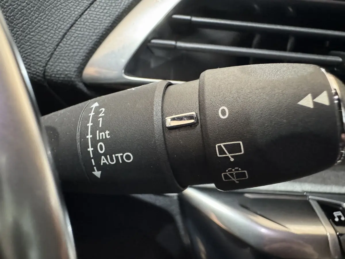 Gros plan sur la commande des essuie-glaces du Peugeot 3008 gris clair, avec marquages blancs et bouton chromé.