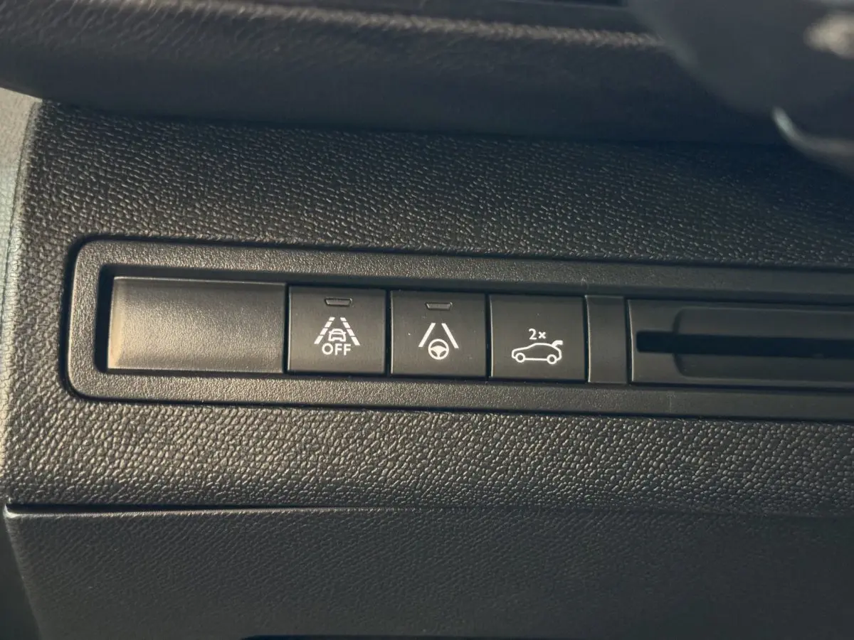 Gros plan sur les boutons de commande d’aide à la conduite dans l’habitacle du Peugeot 3008 gris clair.