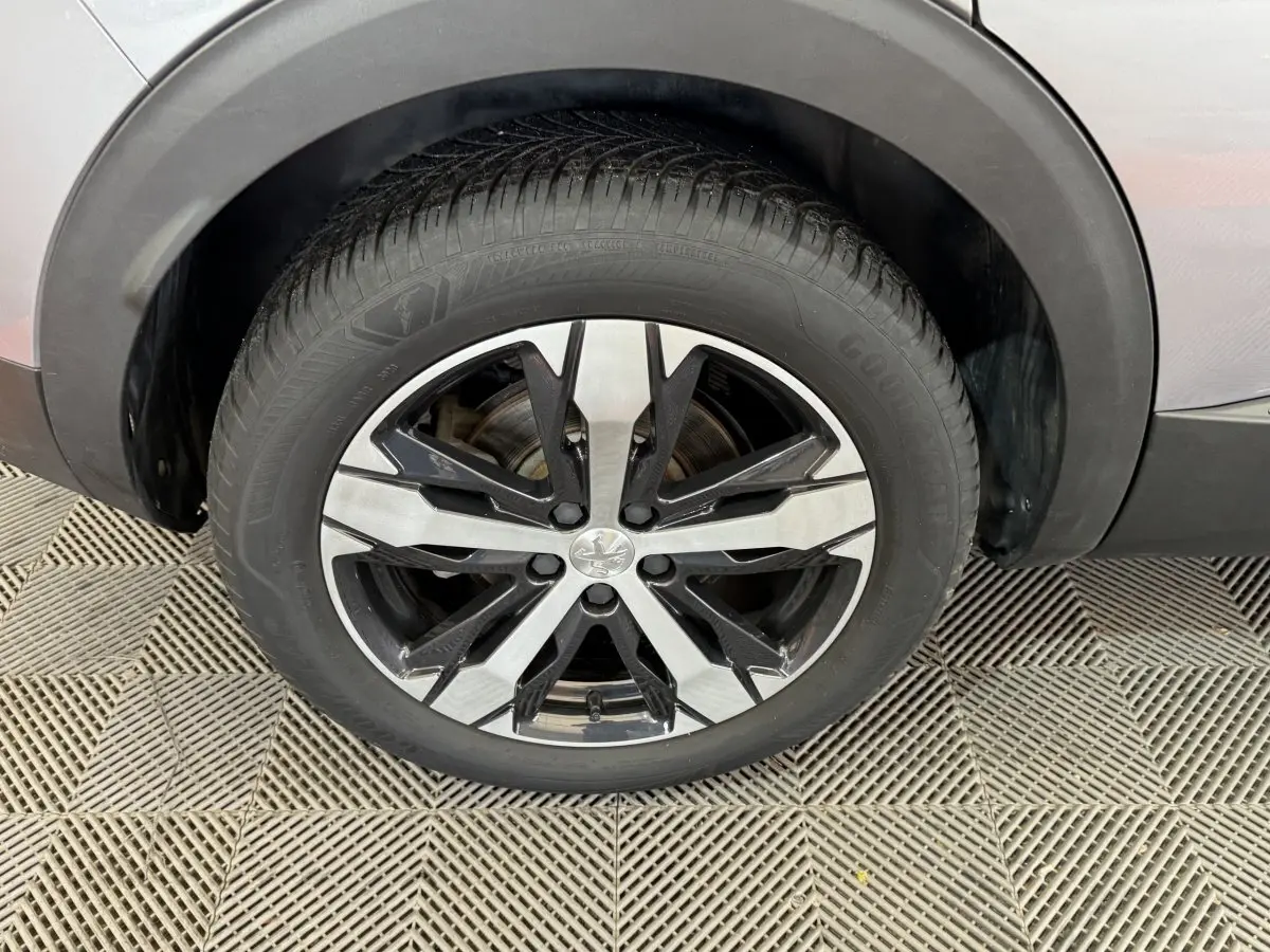 Gros plan sur la roue avant droite du Peugeot 3008 gris clair, jante alliage bicolore au design moderne.